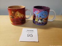 Two Disney character mugs side by side, Lion King on the left and Aladdin on the right