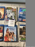 Photo showing 5 items: four DVD/Blu-ray cases including Sisterhood of the Traveling Pants 2, The Hurt Locker, The Secret Life of Walter Mitty, and one unidentified DVD, plus one Wii game Just Dance 4.