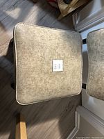 Top view of the square seat cushion showing grey textured fabric and a small lot number tag.