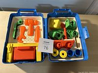 Photo of open blue plastic carrying case containing colorful plastic toy tools and building pieces arranged in molded spots inside.