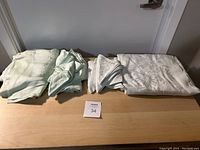 Photo of folded wedding fabrics including light green and white pieces, laid on a table with lot number 34 in front.