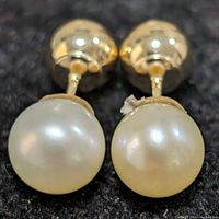 Close-up front view of one reversible 10K gold earring with fresh water pearl under natural light showing pearl detail and gold backing.