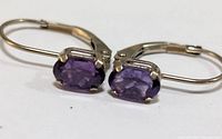 Close-up front view of earrings showing purple amethyst stones and 10K gold lever back closure.