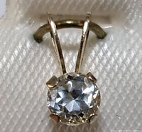 Close-up photo showing the round faceted clear light blue aquamarine gemstone in a 10K gold setting with four prongs.