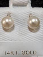 Close-up front view of pearl earrings on 14KT Gold marked holder.