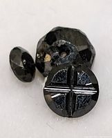 Close-up image of the genuine black diamond showing its faceted surface and distinctive cross-shaped indentation on the bottom side.