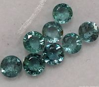 Close-up view showing the light bluish-green round-cut emerald gemstones, highlighting clarity and color.