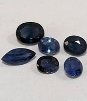 Six loose sapphires of varying shades and cuts on white background