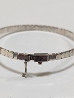 Close-up photo of the bracelet's clasp showing the square link design and safety latch.