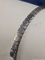 Close up image showing the linked segments of the silver bracelet with smooth flat surfaces and polished finish.