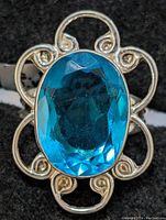 Close-up image of the ring top showing the oval faceted blue quartz gemstone and the filigree sterling silver setting.
