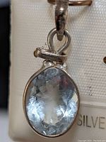 Close-up of oval aquamarine stone set in sterling silver pendant.