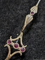 Close-up of one silver ring with three round ruby stones forming a cluster and shell-shaped decorative silver elements with additional ruby accents.