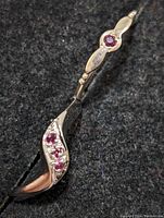 Close-up of two sterling silver rings with ruby stones on dark fabric showing side and top profiles.