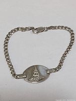 Full view of the sterling silver chain bracelet with oval plaque and lobster clasp.