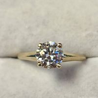 Front view of ring showing round moissanite and four-prong setting on yellow gold shank