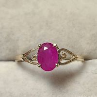 Front view of the 10K yellow gold ring with oval ruby gemstone showing setting and band decoration.