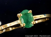 Front view of ring showing oval green emerald in four-prong setting on a yellow gold band