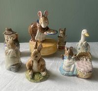 Front view of the eight Beatrix Potter character figurines including the music box, displayed on a white cloth background.