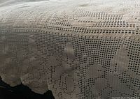 Close-up of the scalloped edge and rose pattern of finished filet crochet bedspread.