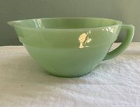 Side angle view of the vintage Fire-King Jadeite green batter bowl showing handle and pour lip.