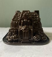 Front view showing detailed haunted manor facade with pumpkins on the base and main entrance with arch and roof shingles.