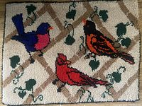 Full view of the hooked acrylic yarn rug with all three birds and the lattice background.