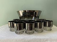 Set of eleven silver fade glasses arranged in front of a large silver-tone punch bowl, showing size and style of the set.