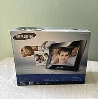 Front of Samsung SPF-75H photo frame box showing product image, branding and key features. 7 inch wide digital photo frame.