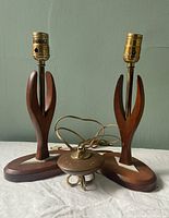 Two wooden midcentury modern style table lamps with sculptural hand-shaped bases, white chevrons on bases, visible electrical cords, no lamp shades.