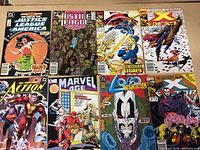 Photo shows eight comic books from Marvel and DC Comics arranged in two rows. Titles include Justice League, X-Men, Action Comics, Marvel Age, and Fantastic Four.