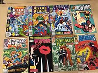 Eight comic books laid out showing covers: two Justice League, four Avengers, one Iron Man, one Wolverine, and one Fantastic Four.