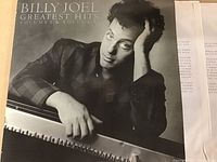 Front cover of the Billy Joel Greatest Hits Volume I & Volume II double vinyl LP featuring a black and white image of Billy Joel at a piano.