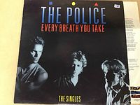 Front cover of The Police vinyl record titled The Singles featuring Every Breath You Take showing band photo and colorful graphics on black background.