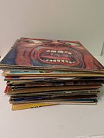 Stack of assorted vinyl records showing some colorful and worn album jackets