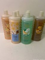 Six bottles of Avon Bubble Delight bubble bath soap in various scents and colors, arranged upright in a row.