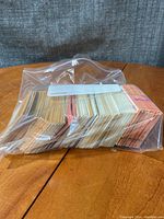 Large stack of baseball cards contained in a transparent plastic bag, showing the card edges and some colored backs and fronts.