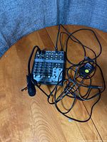 Overview of mixer unit on wooden surface with attached microphone and cables spread out.