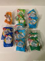 Twelve Disney McDonald's character toys in original plastic packaging arranged on flat surface.