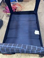 Top view of blue padded mattress inside bassinet with grid pattern