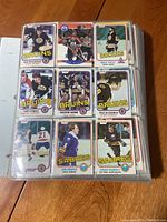 Photo showing a page of hockey cards with players from Bruins, Sabres, and Rockies, stored in a binder sleeve.