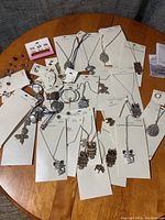 Overview of assorted new jewelry pieces on table, showing various animal-themed necklaces and earrings on white packaging cards with some tangled.