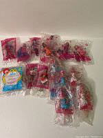 Fifteen Barbie dolls McDonald's toys sealed in individual pink-themed plastic packaging with McDonald's branding, displayed in two rows on a white background.