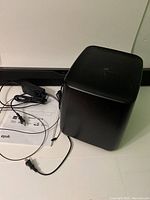 Sound bar, subwoofer, power adapter and cables laid out on a white surface with user manual visible.