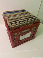 Red milk crate containing 74 assorted vinyl record LPs