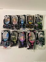 Front view of all 10 toys in original unopened packaging, laid out in two rows. Packaging is black with character images and number labels.
