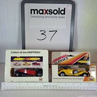 Two friction-powered collectible car models in original sealed packaging displayed with measurement ruler.