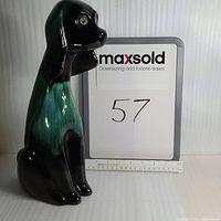 Front view of the large ceramic dog figurine, showing glossy green and black glaze and seated posture.