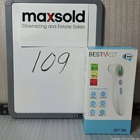 Photo showing the boxed BestMed infrared forehead thermometer next to a MaxSold board with lot number 109