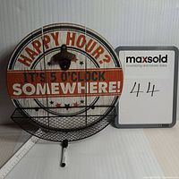 Full view of round wooden sign showing text 'Happy Hour? It's 5 o'clock somewhere!' with metal bottle opener and black mesh basket attached.